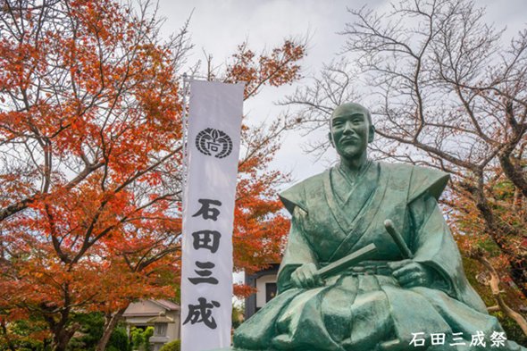紅葉を背に立つ石田三成公の銅像